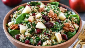 Quinoa spinach salad with apples and cranberries served in a bowl